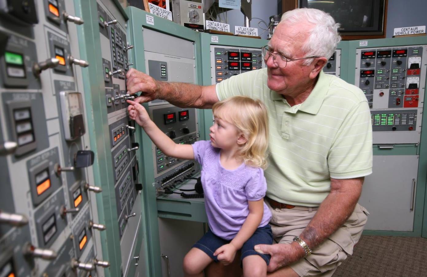 A child and an older visitor operate controls on a launch console.