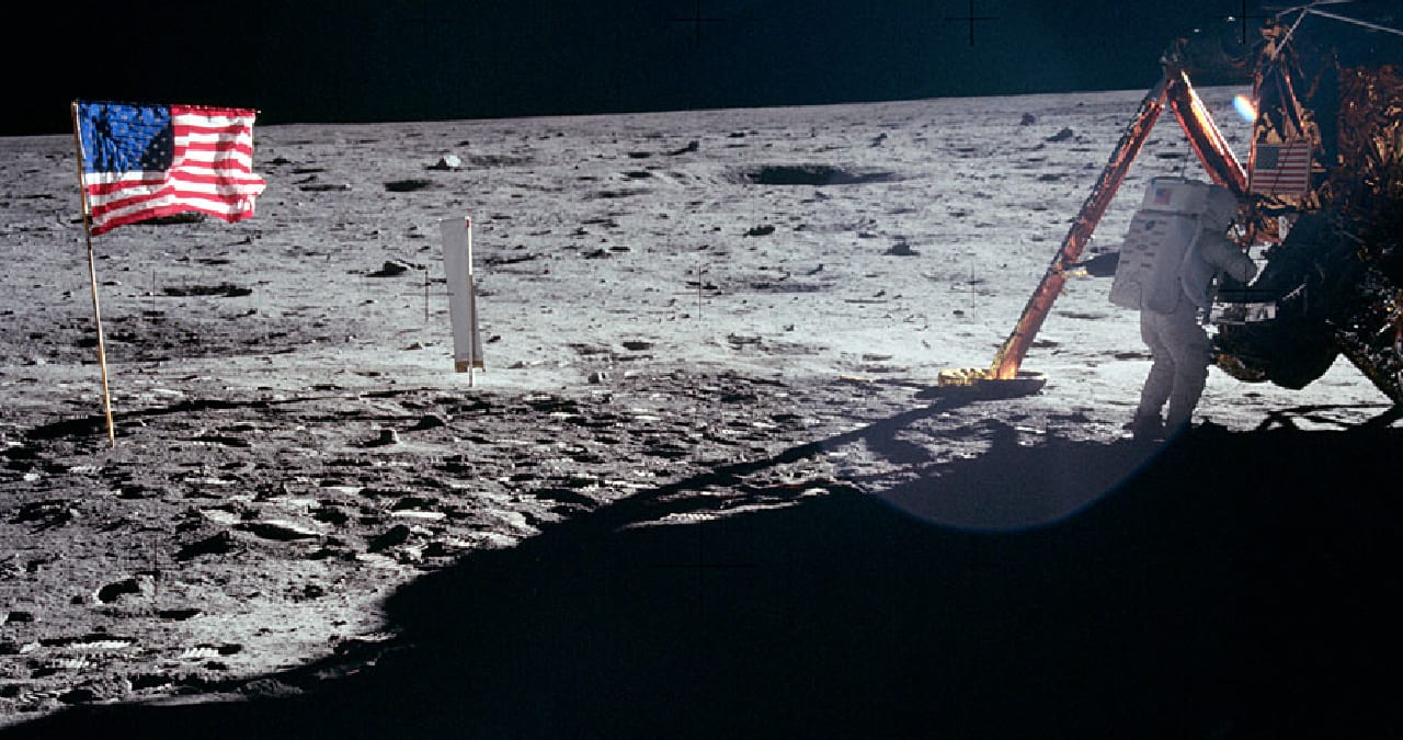Apollo 11 lunar surface with an astronaut, United States flag, and lunar module footpad.